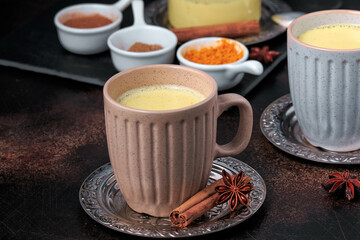 Easy Healthy Golden Milk, Turmeric Latte over dark background. Spices for ayurvedic treatment. Alternative medicine concept.