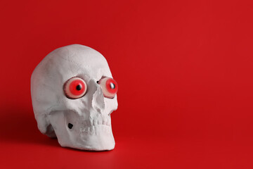 Human skull with fake eyes on color background