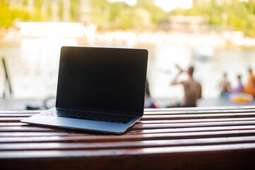 laptop on the street on the wooden bench on the bright background 