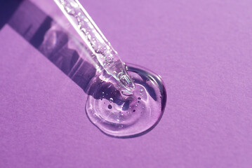 Pipette close-up on a purple background in soft focus. Beautiful shadow in the sunlight. Skincare products , natural cosmetic. Beauty concept for face and body care