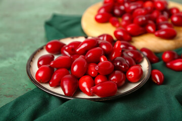 Plate with ripe red dogwood berries on table, closeup