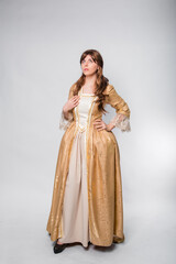 Fototapeta na wymiar A full-length portrait of a girl in a golden rococo gown posing isolated on a white background.