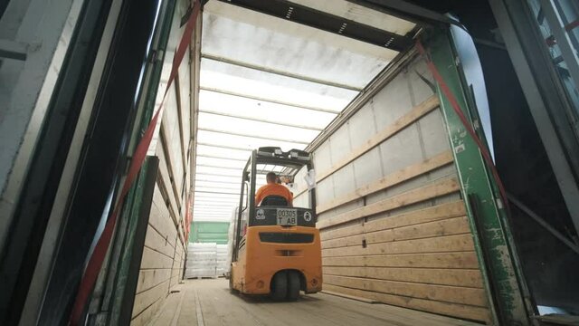 Forklift driver transports packaged water bottles in warehouse
