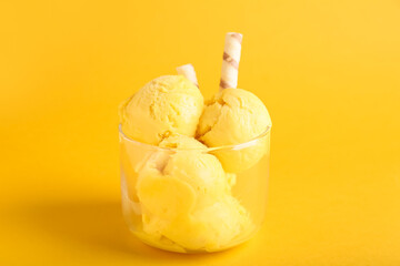 Bowl of delicious mango ice cream balls on color background