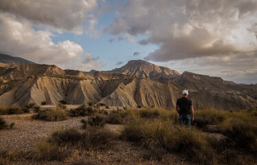 Fototapeta na wymiar Rear view of adult man on Tabernas desert in Almeria, Spain, against cloudy sky