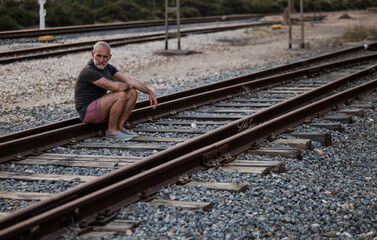 Man sitting on railway track during sunset