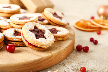 Board with tasty Linzer cookies on grunge background, closeup