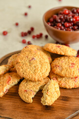 Wooden board with delicious cranberry cookies and berries on light background, closeup