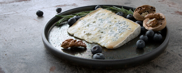 ceramic dish with gorgonzola cheese, rosemary and blueberries on the table