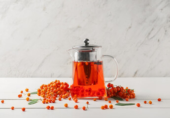 Glass teapot with hot rowan tea and berries on light background - obrazy, fototapety, plakaty