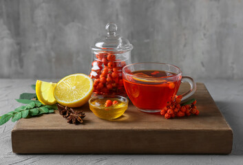 Composition with glass cup of tasty rowan tea, honey and lemon on grunge background