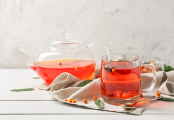 Glass cup and teapot with tasty rowan tea on table