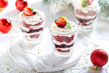 Dessert with red sponge cake, currant jam and cream, garnished with kaleunik in glass glasses, selective focus. The concept of a dessert for the holiday.