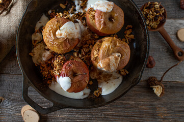 Breakfast with baked apple, granola, yogurt and cinnamon on rustic wooden table