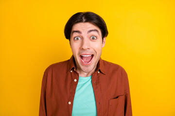 Photo of funny impressed young man wear brown shirt open mouth isolated yellow color background