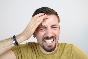 Young man with adhesive bandage plaster on forehead. First aid after accident. 