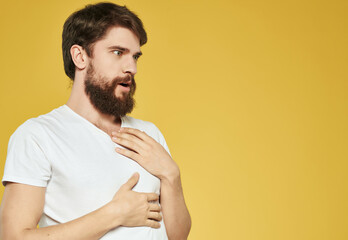 Man in a white t-shirt hand gestures anger yellow background
