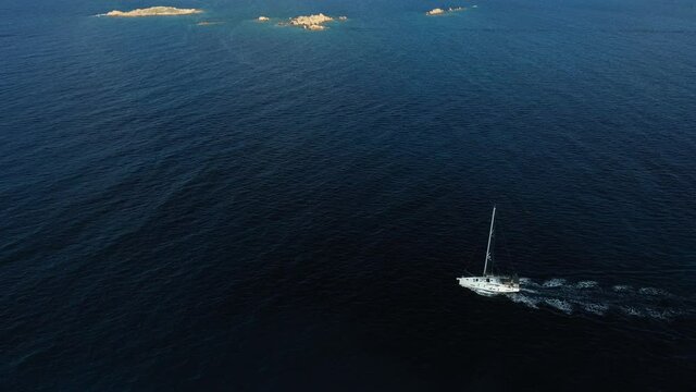View from above, stunning aerial view of a sailboat sailing on a blue water during a sunny day. Costa Smeralda, Sardinia, Italy.