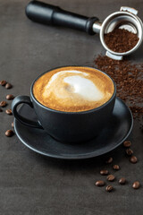 Relaxing latte coffee in black porcelain cup on stone table