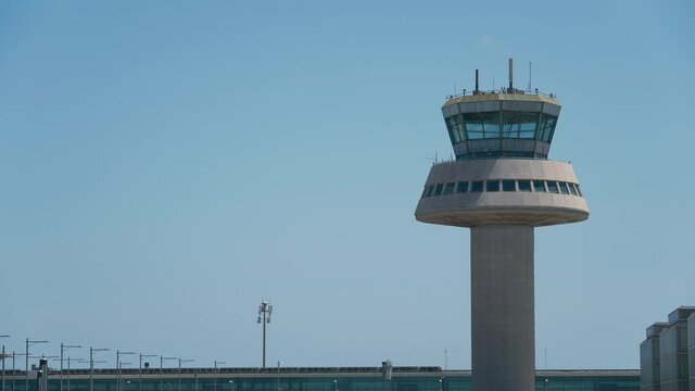 Orange airplane taking off next to an air traffic control tower