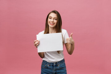 Young beauty woman hold blank card and showing thumbs up over pink background