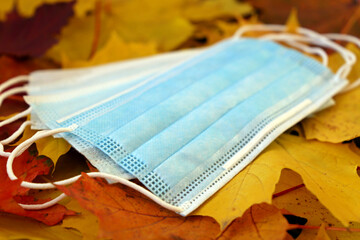 Medical disposable masks on maple leaves. Concept of protection during coronavirus infection in autumn cold season