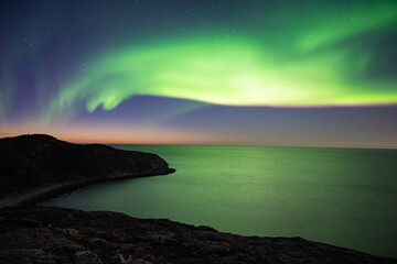 Fototapeta na wymiar Bright green nortern lights on the shore of Baltic sea in Teriberka
