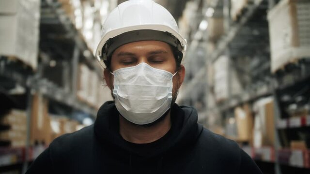 Portrait Of A Frontline Worker In A Warehouse. Manager Of Warehouse Standing Next To Manufactured Storehouse Stock Or Hardware Store Racks. Close-up Portrait. Concept Of Transportation And Logistics.