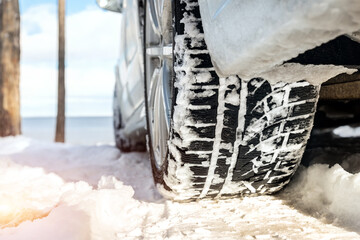 Close-up detail view of car wheel with winter tread tire during driving through slippery snow...