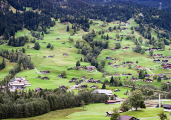 Beautiful Grindelwald village with traditional chalets in the green valley in Swiss Alps