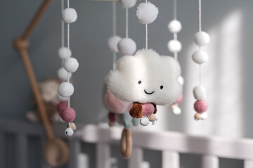 Baby crib mobile with smiling clouds and snow. Kids handmade toys above the newborn crib. First...