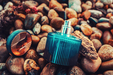International Fragrance Day. A open blue glass perfume bottle on a wet pebble beach. Close-up....