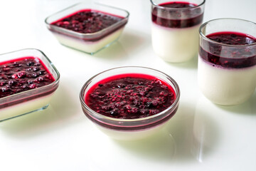 Delicious panna cotta with with raspberry sauce on white table