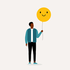 Be Positive Concept. Young Black Man Holding Yellow Smiley Face Balloon. Good Vibes.
