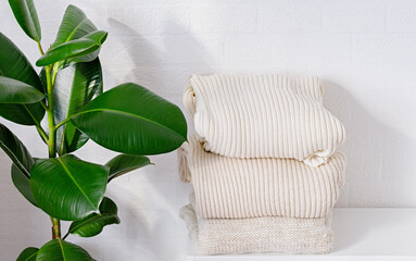 Three warm white sweaters on the shelf. Autumn and winter clothing. Close up. Copy space.