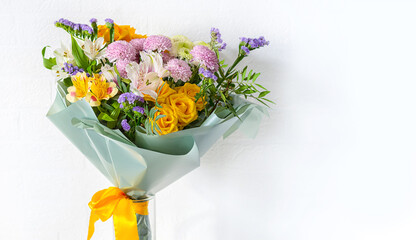 A beautiful flower bouquet is tied with a yellow silk ribbon. White background. Copy space, close up.