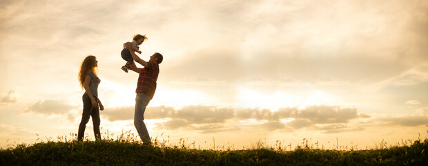 Caucasian family mom dad and little son at sunset. Silhouettes of parents and toddler boy on the...