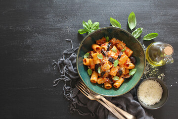 Pasta alla norma - Italian pasta with eggplante, tomato sauce and parmesan cheese on dark table. Top view. Healthy food.