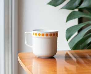 Mid-century modern porcelain cup on a wooden table with philodondendron in the background