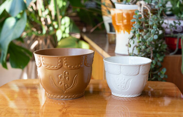 Vintage ceramic empty flower pots on a wooden table, in the background plants