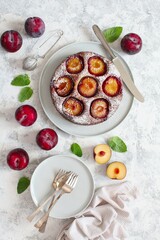 Tasty cake with plums on light background. Top view. Copy space.