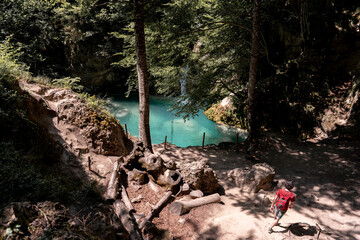 Young brunette man is exploring a hidden blue lake in the middle of the woods, concept of adventure