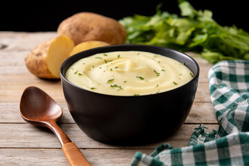 Mashed potatoes in a bowl on wooden table.	
