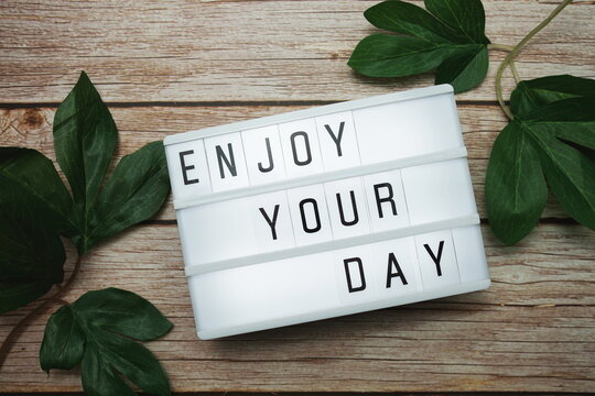 Enjoy Your Day text on lightbox on wooden background