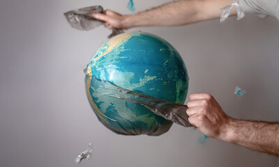 Men's hands tear off a plastic bag from the globe of planet Earth. The concept of environmental...