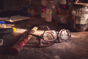 Deux paires de lunettes déposées sur un établi d'atelier de restauration d'art.