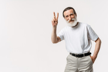 European senior man with beard showing peace gesture at camera