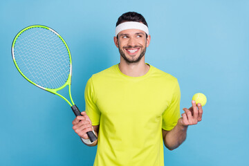Portrait of attractive cheerful guy playing tennis holding ball thinking pass isolated over bright blue color background