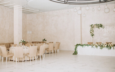 Wedding. Banquet. Chairs and a round table for guests, served with cutlery, flowers and utensils and covered with a tablecloth. Beige colors