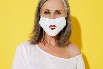White senior woman posing in face mask with red kiss